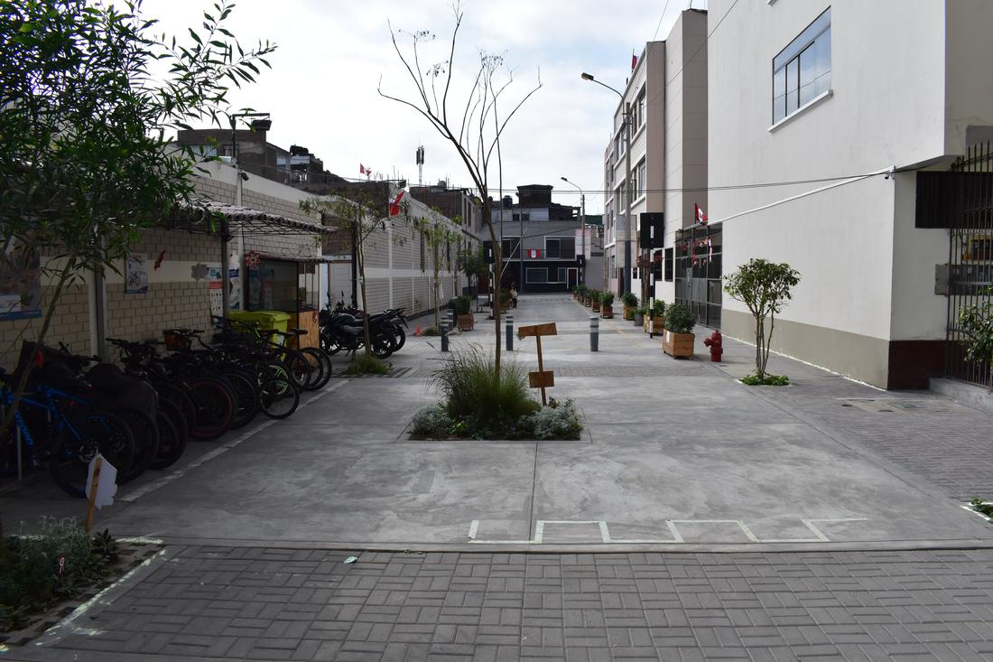 A pedestrianised street with bike parking, bollards and a planted island