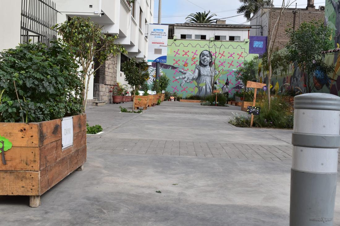 After: the same street as a pedestrian space with trees, planters and a mural of a girl reaching out