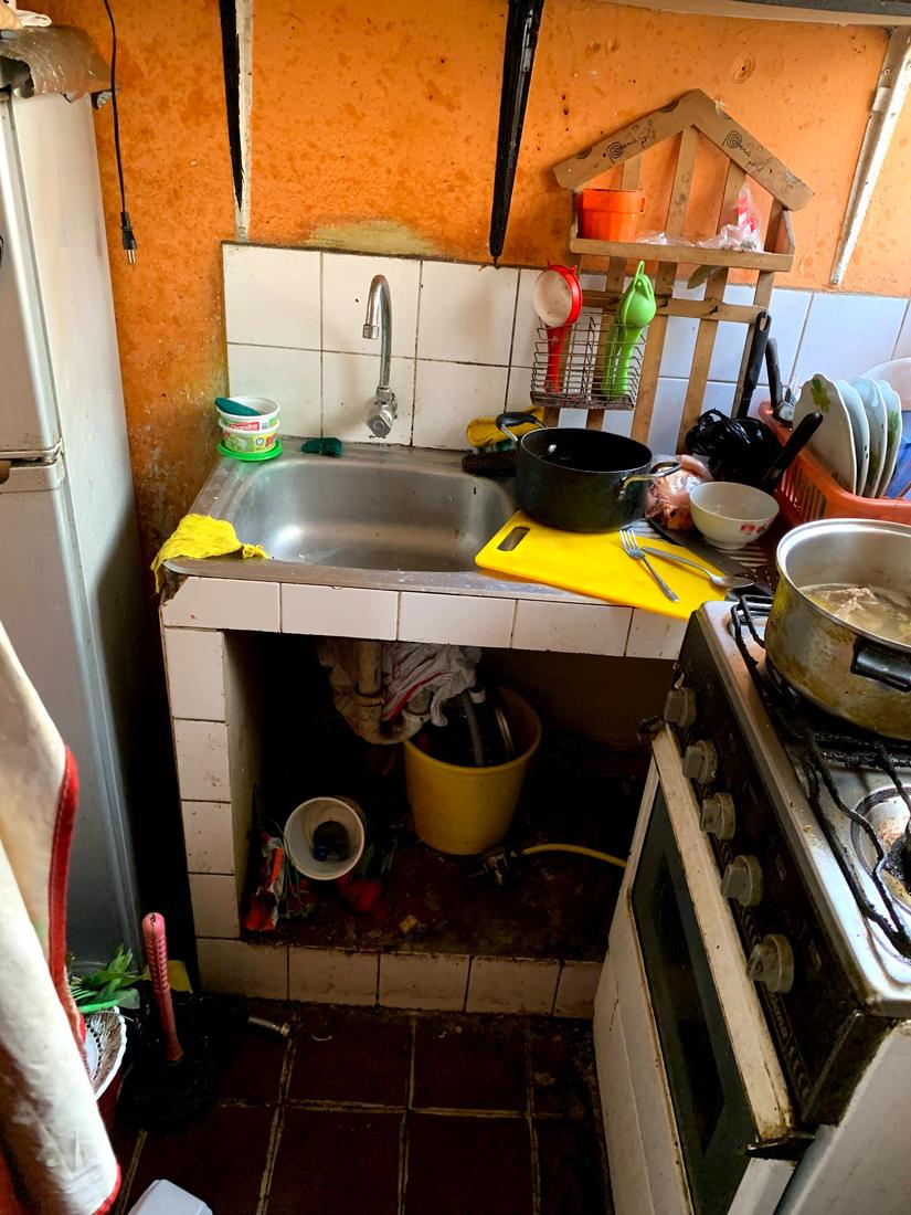 Before: a cramped kitchen with damp, stained walls, a worn sink and an old gas stove
