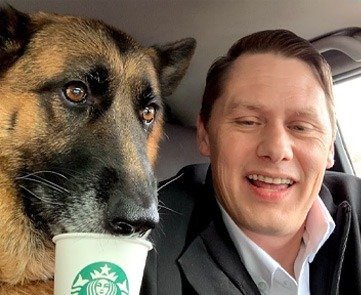 Chris with Bandi, his German shepherd, sharing a coffee cup in the car