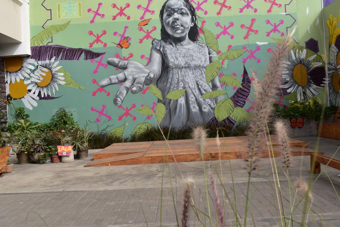 Mural of a young girl reaching out a hand, with a wooden platform below