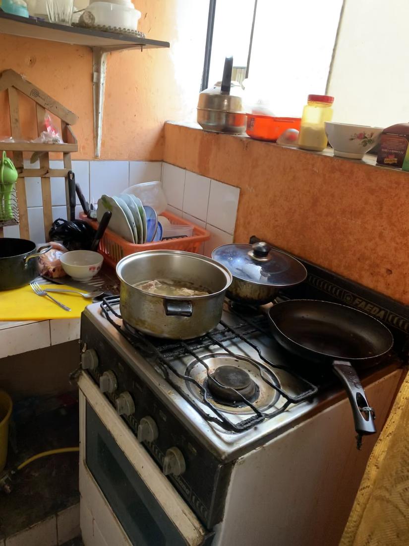 Pots on a worn gas stove beside a dish rack